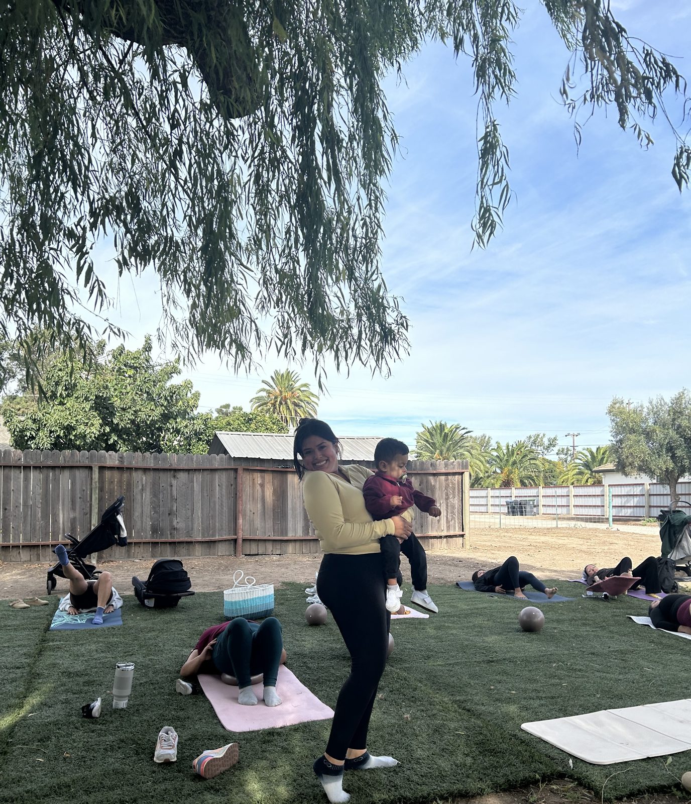 Briana holding her son at an outdoor Pilates + Play Date session